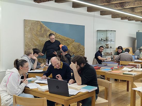 Das Foto zeigt eine Gruppe Studierender in Diskussion mit Oskar Kaelin