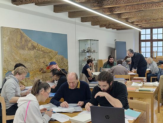 Das Bild zeigt eine Raumübersicht mit mehreren Studierendengruppen, die an einer Übersetzung arbeiten